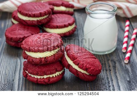 Red velvet sandwich cookies with milk on a wooden table