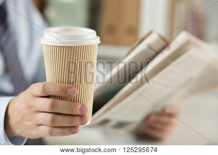 Closeup Of Businessman Reading News And Holding Coffee Cup