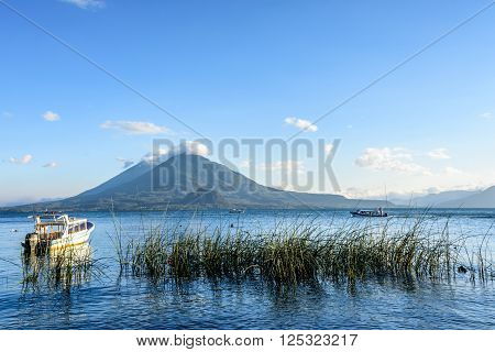 Evening light on boats & two volcanoes Atitlan & Toliman at Lake Atitlan, Guatemala.