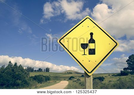 Wine bottle road sign on empty dirt street with vintage filter effect and nature landscape background.