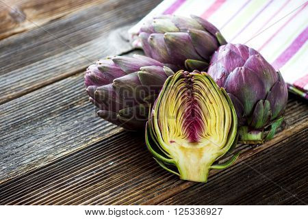 Organic Artichokes On  Rustic Wooden Board