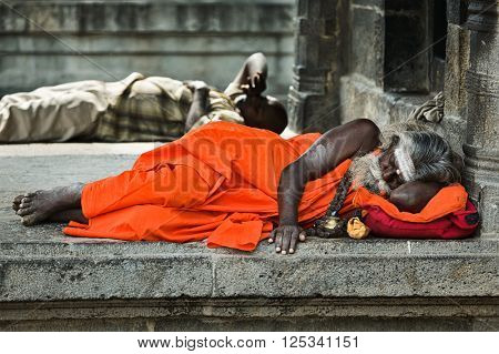 TIRUVANAMALLAI, INDIA - JANUARY 7, 2010: Sadhu -  religious ascetic or holy person - sleeping in Hindu temple Arunachaleswar. Tiruvanamallai, Tamil Nadu, India