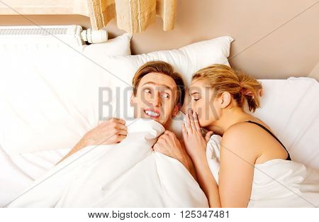Woman whispering to her husband and he laughting