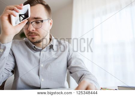 business, startup, stress, problem and people concept - businessman or creative male worker with smarphone at home office