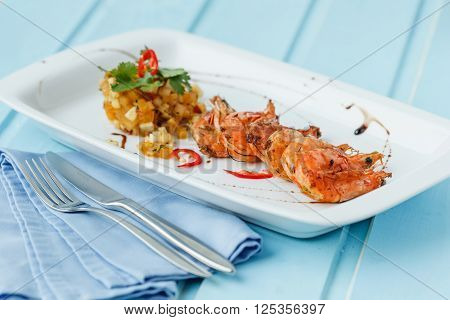 Grilled shrimps with fried vegetable on blue wood background