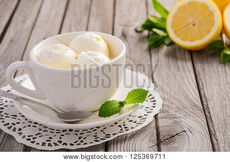 Lemon ice cream in white cup on rustic wooden background, selective focus, copy space