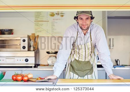 Young male entrepeneur standing confidently in his food stall where he makes and sells takeaway food