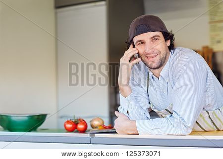 Entrepeneur smiling while making a call on his phone from his takeaway food business