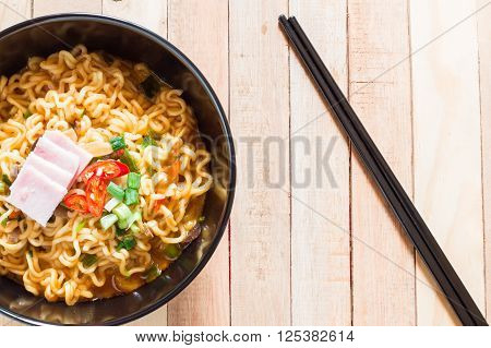 Top view of korean noodles(Ramyun) in black bowl on wooden table.