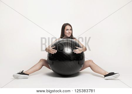 Portrait of young attractive woman doing exercises. Brunette with fit body exercising with fitness ball. Series of exercise poses.