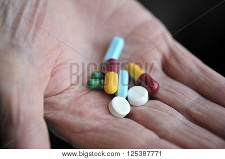 Old age pensioner holding daily drug medications.