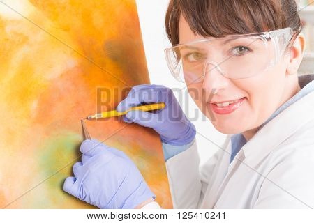 Artwork conservator at work with old painting wearing protective suit