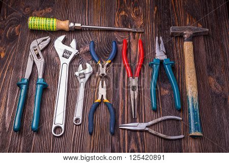 Different Working tools on a wooden table - a hammer wire cutters pliers chisels and wrenches