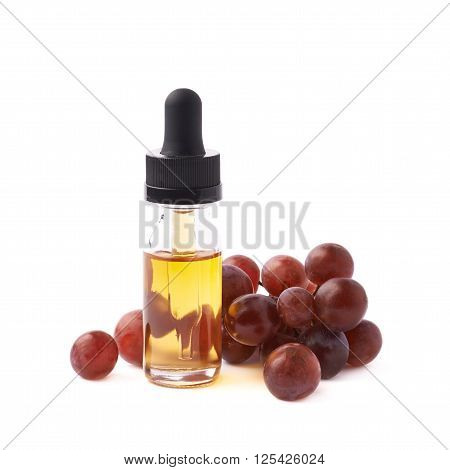 Grape seed oil essence in a small bottle with a pipette, surrounded with the multiple dark grapes, composition isolated over the white background