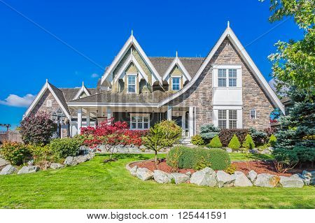 Custom built luxury house with nicely trimmed and designed front yard, lawn in a residential neighbourhood in Canada.