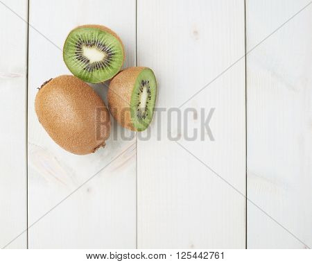 Two sliced kiwifruits or chinese gooseberry kiwi fruits composition over the white wooden boards surface