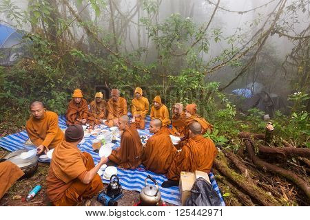 CHIANG DAO, THAILAND, JANUARY 06, 2015: Group of Buddhist monks praying for new year celebration before an outdoor lunch in the foggy wild nature of the Chiang Dao mount in Thailand.