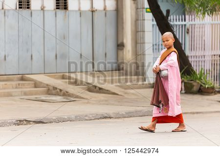 MANDALAY,MYANMAR,JANUARY 17, 2015: A young Buddhist nuns is walking in the streets of Mandalay, Myanmar (Burma).