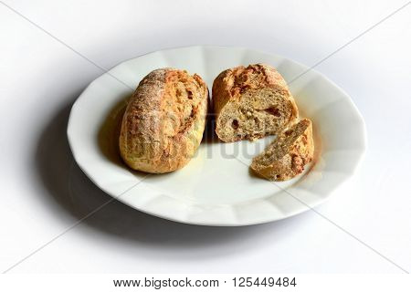 two pieces of multigrain bread roll on white plate on white table.