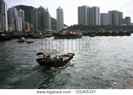 ABERDEEN / HONG KONG - CIRCA 1987: A wooden motorboat enters the harbor at the Aberdeen Floating Village in Hong Kong.