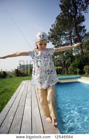 Portræt af en lille pige gå ved siden af en pool