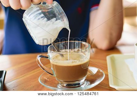 Morning cup of hot coffee with cream on table