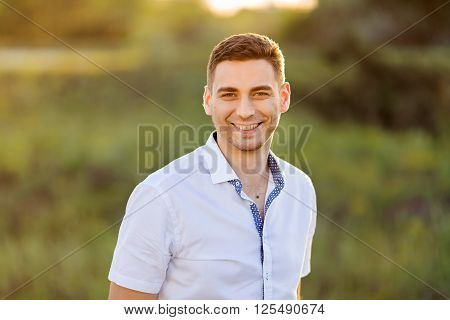 Portait of a young smile man. Close up of a gorgeous guy, outdoors