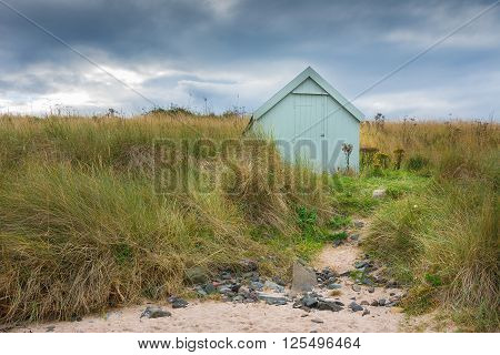 Lonely beach hut with footpath leading to it from the beach under stormy sky