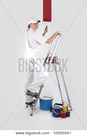 Portrait of a painter on a ladder painting a white wall