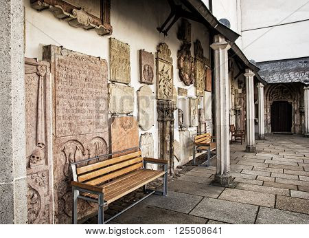 Detail of courtyard of famous Saint Stephen's cathedral in Passau Germany. Memory plaques at the wall and benches. Architectural theme.