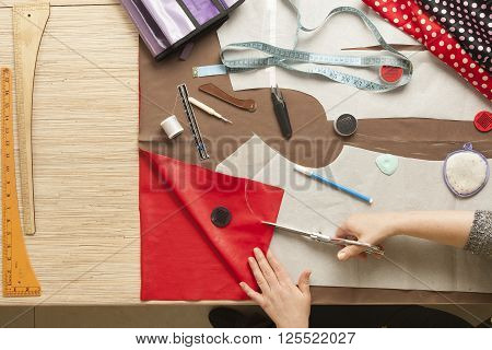 Desk designer fashion. Fashion designer starts cutting fabric to create fashionable clothes.