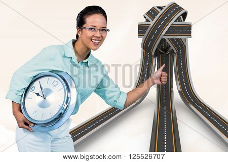 Delighted businesswoman holding a clock against orange background