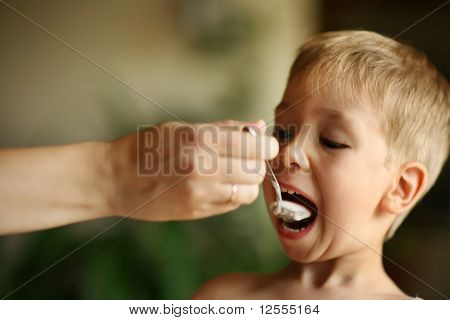 Weibliche Hand Fütterung kleiner Junge mit Löffel Jogurt