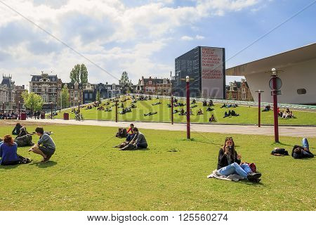 Amsterdam, Netherlands - May 6: This is the Museum square with a building the Stedelijk Museum and the lawn with vacationers people May 9, 2013 in Amsterdam, Netherlands.