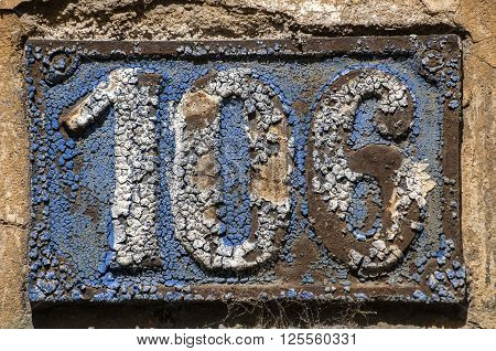 Old retro weathered cast iron plate with number 106
