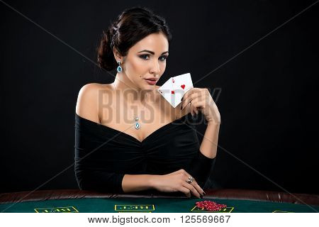 sexy woman with poker cards and chips. Female player in a beautiful black dress. girl sitting at the poker table