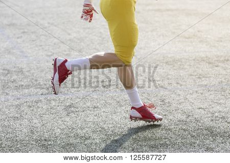 Unrecognizable football player running on the green grass court