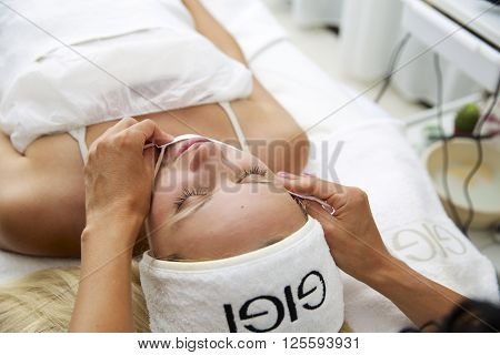 Beautiful young woman during facial massage in cosmetic salon close up