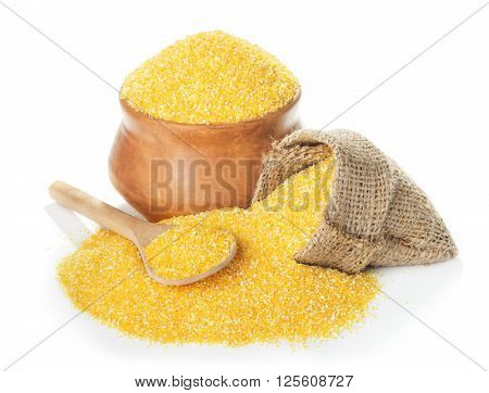 Uncoocked corn grits polenta in bowl and spoon close-up isolated on white background