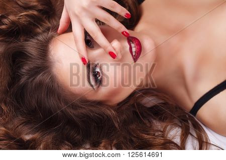 Young sexy woman in bra lying on the bed. She covers her eyes with her hand. Bliss. Girl flirts. Close-up portrait.