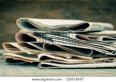 Newspapers and magazines on old wood background. Toned image.