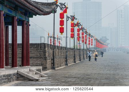 Xian China - October 16 2013: View with tourists on the West Gate of Xian City Wall one of the oldest and best preserved Chinese city walls in Xian of Shaanxi Province China. Misty day.