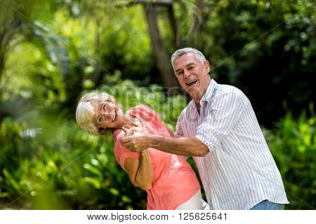 Portrait of senior couple enjoying while dancing in yard