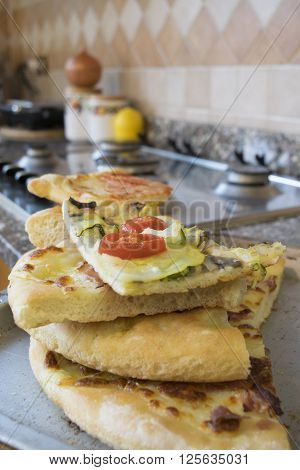 pieces of assorted homemade pizza on a hob in a domestic kitchen