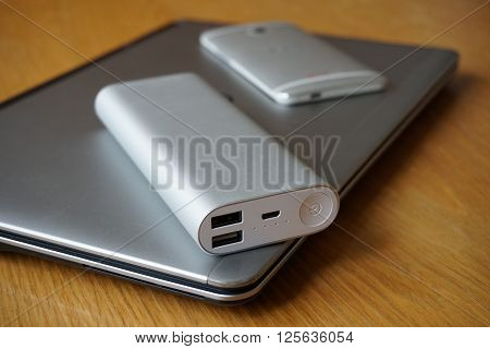 Modern mobile office with metal aluminum devices - cell phone, power bank (external battery) and silver ultrabook (thin portable laptop)