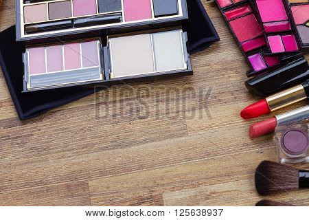 lipsticks, maskara, eye shadows  on wood, top view with copy space