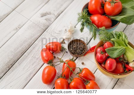 close up of fresh red delicious tomatoes with greenery on an old wooden background