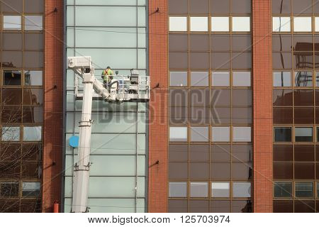 Workers is engaged in restoration of the modern multi-storey building in Helsinki, Finland