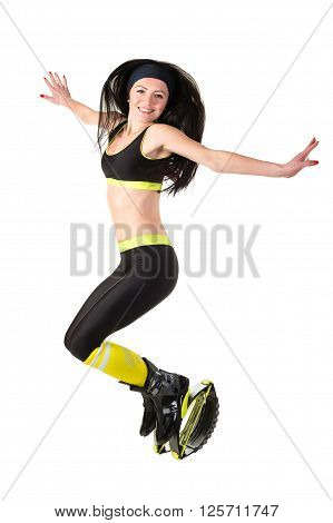 Smiling brunette girl with long hair in a black sportswear jumping in a kangoo jumps shoes. isolated on a white background.