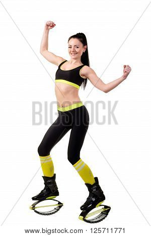 Smiling brunette girl with long hair in a black sportwear and kangoo jumps shoes showing a muscles on her hands. isolated on a white background.